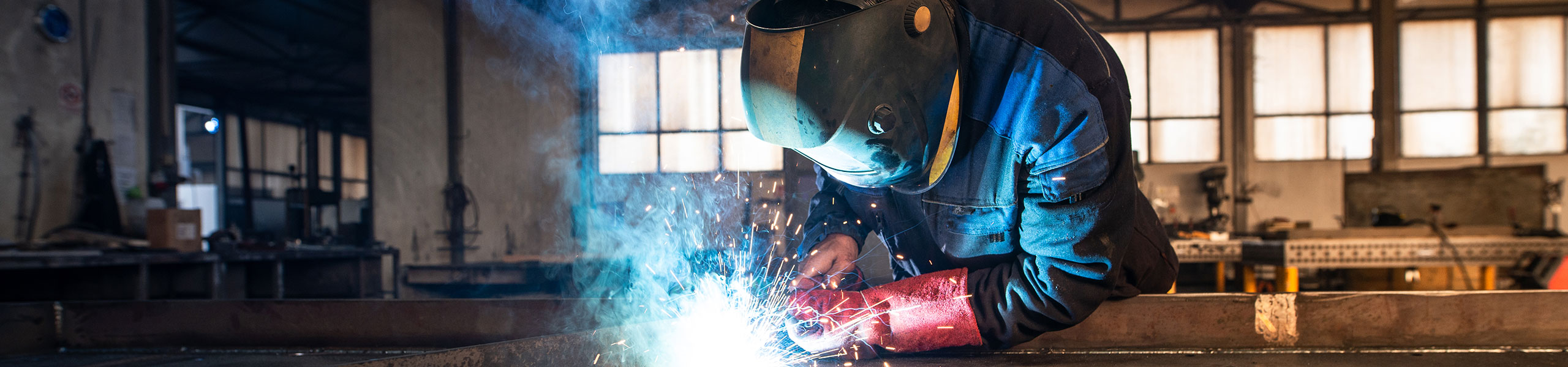 Professional industrial welder welding metal parts in a metalworking factory